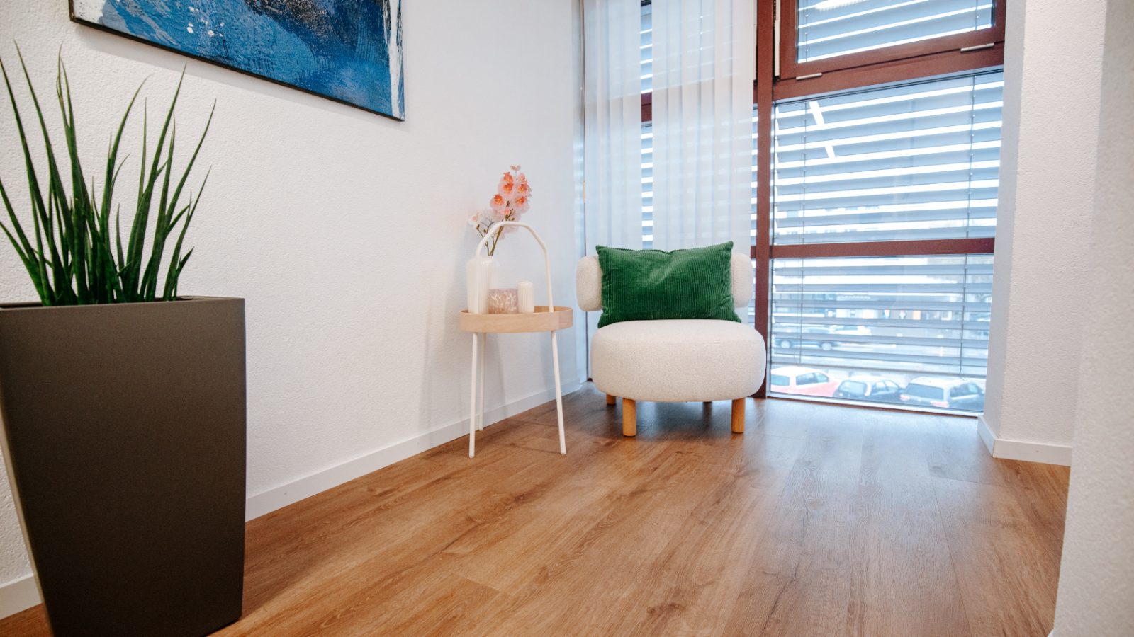 Heller Wartebereich mit Sessel am Fenster in der Praxis Dr. Maienfisch AG